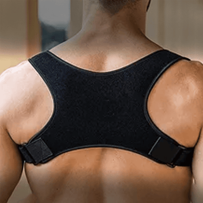 A man viewed from the back wearing a black posture corrector brace on his shoulders and upper back.